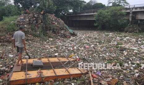 Seorang warga berdiri di atas sampan di antara sampah yang menumpuk di sebuah situ (ilustrasi) 