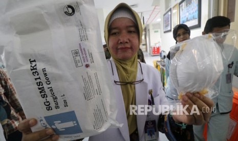 Seorang dokter memperlihatkan masker dan baju pelindung sekali pakai di ruang isolasi Rumah Sakit Umum Daerah (RSUD) Gambiran, Kota Kediri, Jawa Timur. Petugas Kemenkes lakukan uji petik virus Corona pada dua pasien TBC. Ilustrasi.