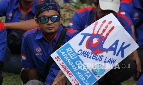 Seorang buruh membawa poster Tolak Omnibus Law saat mengikuti aksi unjuk rasa di Depan Istana Merdeka, Jakarta, Kamis (30/1/2020).