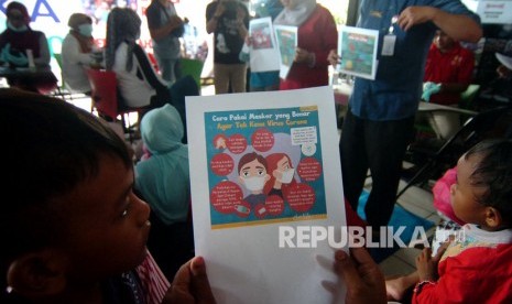 Seorang anak bersama orangtuanya membaca tentang bahaya dan penanganan wabah virus novel Coronavirus (nCoV) saat sosialisasi dan pengobatan gratis di sekolah terminal Sakila Kerti di Terminal Kota Tegal, Jawa Tengah, Jumat (31/1/2020).