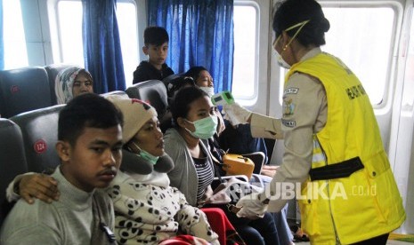 Seorang Petugas medis (kanan) memeriksa suhu tubuh penumpang menggunakan thermometer non kontak di dalam kapal yang baru tiba dari Melaka, di Pelabuhan PT Pelindo I Dumai di Dumai, Riau, Sabtu (01/2/2020).