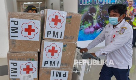 Petugas mendorong troli bermuatan kardus yang berisi masker bantuan dari PMI pusat yang baru tiba di Bandara Raden Sadjad, Ranai, Natuna, Kepulauan Riau, Selasa (4/2/2020).