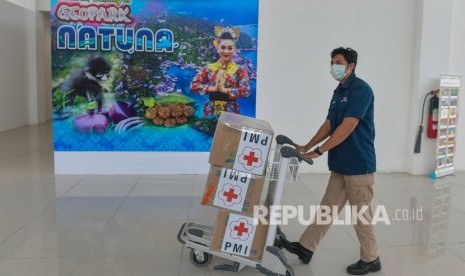 Petugas mendorong troli bermuatan kardus yang berisi masker bantuan dari PMI pusat yang baru tiba di Bandara Raden Sadjad, Ranai, Natuna, Kepulauan Riau, Selasa (4/2/2020). 