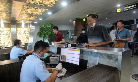 Dua petugas Imigrasi memproses paspor penumpang pesawat yang tiba di Terminal Kedatangan Internasional Bandara Supadio di Kabupaten Kubu Raya, Kalimantan Barat, Kamis (6/2). Pemerintah Indonesia membatasi akses masuk sementara terhadap beberapa negara di Afrika