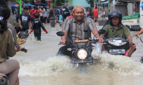 Warga melintasi genangan banjir di sejumlah wilayah di Kabupaten Cirebon, Jawa Barat.