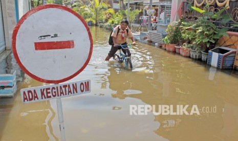 Siswa melintasi banjir yang tak kunjung surut di Desa Kedungbanteng, Tanggulangin, Sidoarjo, Jawa Timur, Jumat (7/2/2020). 