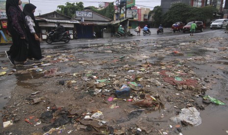 Sejumlah warga melintasi sampah yang berserakan di Jalan Mampang, Sawangan, Depok, Jawa Barat (lustrasi)