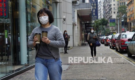 Seorang warga mengenakan masker melintasi pertokoan di Hong Kong, Senin (10/2).