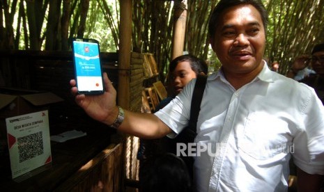 Kepala Perwakilan Bank Indonesia (BI) Tegal M.Taufik Amrozy (kanan) menunjukkan transaksi melalui aplikasi uang elektronik server based, dompet elektronik dan mobile banking saat peluncuran dan implementasi QR Code Indonesian Standard (QRIS) untuk desa wisata di Pasar Slumpring, Desa Cempaka, Kabupaten Tegal, Jawa Tengah, Ahad (16/2/2019).