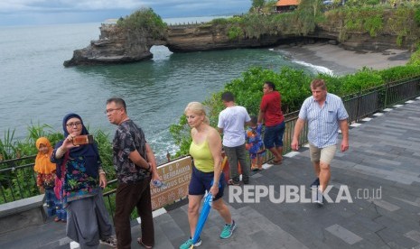 Wisatawan menikmati pemandangan di area objek wisata Tanah Lot, Tabanan, Bali, Ahad (16/2). Dinkes Bali menyebut terlalu berlebihan kalau masyarakat  ke mana-mana pakai masker.