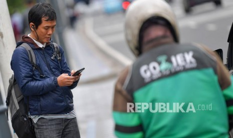 Seorang calon penumpang menanti pengemudi ojek online di Jalan Thamrin, Jakarta, Senin (17/2/2020). 