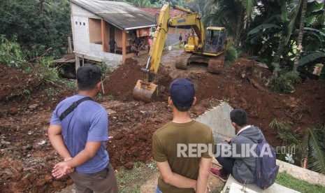 Sejumlah warga melihat petugas dengan alat berat mengeruk jalan yang longsor di kawasan Kalimulya 3, Depok, Jawa Barat (ilustrasi)