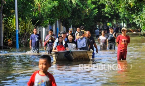 Sejumlah warga menaiki perahu saat banjir di Pulomas, Jakarta Timur.