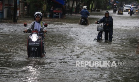 Warga melintasi banjir di jalan Yos Sudarso, Indramayu, Jawa Barat, Senin (24/2/2020).