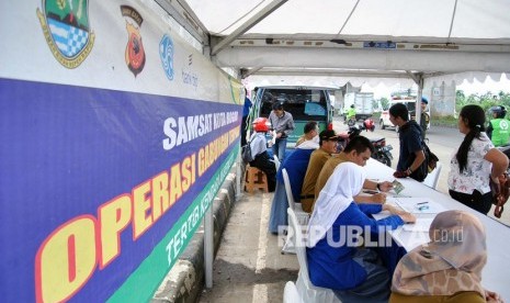 Sejumlah warga yang terkena razia, membayar pajak saat operasi Pajak Kendaraan Bermotor (PKB) di jalan KH Sholeh Iskandar, Kota Bogor, Jawa Barat, Senin (24/2/2020).