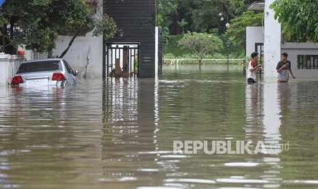 Sudin Kebakaran Jaktim Sedot Air Genangan di Tujuh Lokasi. Warga melintas didepan rumah saat banjir di kawasan Kampung Makasar, Jakarta Timur. Foto ilustrasi. 