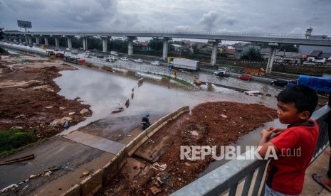 Seorang anak melihat ruas tol Jatibening yang terendam banjir di Bekasi, Jawa Barat, Selasa (25/2). Mengenai penyebab banjir yang melanda sejumlah titik di wilayah Bekasi pada Selasa (25/2), pemprov Jabar mengatakan salah satunya disebabkan oleh curah hujan yang cukup tinggi. 