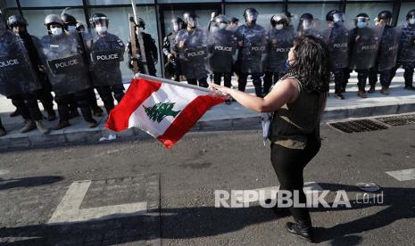  Seorang demonstran anti-pemerintah memegang bendera Lebanon 