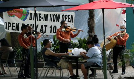 Pengunjung melewati sebuah restoran yang telah dibuka kembali di River Walk di San Antonio, Texas, Rabu (27/5). Texas dibuka kembali oleh warga setelah karantina pandemi virus corona covid19. Foto AP / Eric Gay