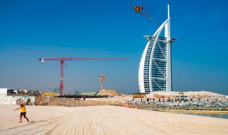 Seorang anak bermain di pantai dengan latar belakang Burj al-Arab di Dubai, Uni Emirat Arab, Jumat (29/5).