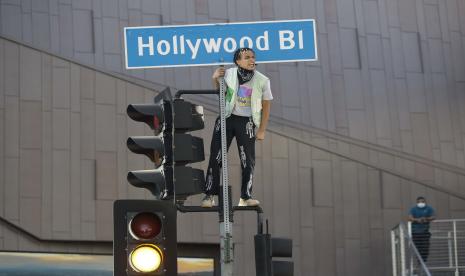 Seorang demonstran memanjat lampu lalu lintas di daerah Hollywood Los Angeles, Ahad (7/6). Mereka melakukan protes terkait kematian George Floyd yang meninggal pada 25 Mei setelah ditahan oleh polisi Minneapolis.  