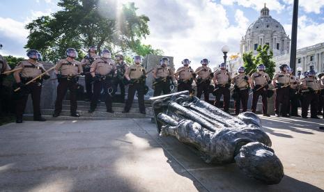 Pasukan Negara Bagian Minnesota mengepung patung Christopher Columbus setelah patung itu dijatuhkan di depan Capitol, di St. Paul, Minnesota, Rabu (10/6). Patung perunggu Christopher Columbus setinggi 10 kaki tersebut dirobohkan dan menjadi amukan massa anti-rasisme terkait protes kematian George Floyd. Leila Navidi/Star Tribune via AP