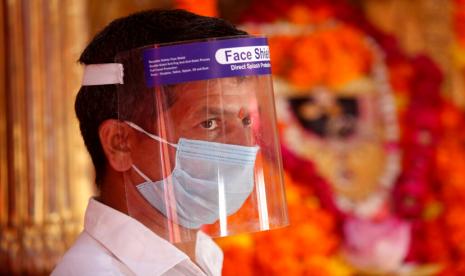 Pendeta hindu menggunakan face shield dan masker di dalam sebuah kuil di Jammu, India, Ahad (16/8).