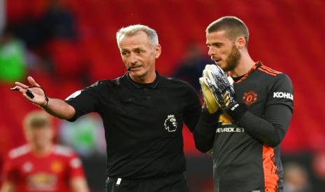 Penjaga gawang Manchester United David de Gea berbicara dengan wasit Martin Atkinson setelah menyaksikan VAR dan menyatakan penalti harus diulang pada laga perdana Liga Primer Inggris, Ahad (20/9).