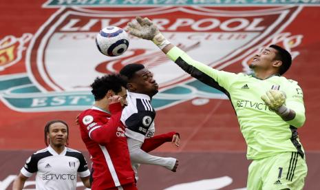 Kiper Fulham Alphonse Areola (kanan) beraksi menghadapi striker Liverpool Mohamed Salah (kiri) dalam lanjutan Liga Primer Inggris, Ahad (7/3). Fulham menang 1-0 dalam pertandingan itu.