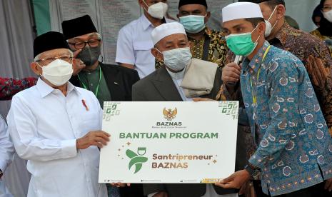 Wakil Presiden Ma’ruf Amin (kiri) menyerahkan bantuan program santripreneur secara simbolis kepada lulusan Pondok Pesantren Nurul Iman Mubarok Irzan (kanan) di Pondok Pesantren Al-Jauharen, Tanjung Johor, Pelayangan, Jambi, Rabu (15/6/2022). Wapres menyerahkan bantuan pengembangan kewirausahaan santri melalui program santripreneur Badan Amil Zakat Nasional (BAZNAS) kepada sepuluh lulusan pondok pesantren di kota itu. 