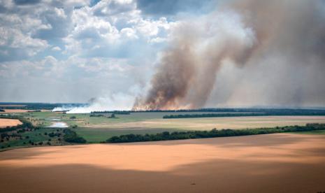 Asap mengepul dari garis depan di mana pertempuran sengit terjadi antara pasukan Ukraina dan Rusia, ladang petani di latar depan, di wilayah Dnipropetrovsk, Ukraina, pada 4 Juli 2022. Gubernur Dnipropetrovsk Valentyn Reznychenko mengatakan tembakan Rusia menewaskan 21 orang di wilayahnya.