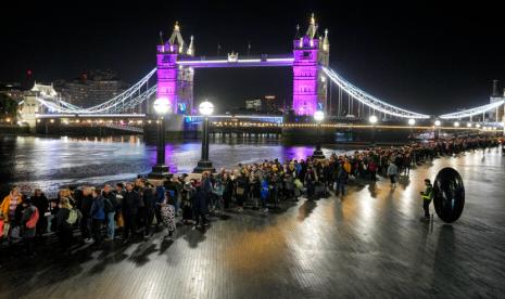 Orang-orang mengantri di depan Tower Bridge untuk memberi penghormatan kepada mendiang Ratu Elizabeth II selama Lying-in State di Westminster Hall di London, Sabtu dini hari, 17 September 2022. Ratu akan disemayamkan di Westminster Hall selama empat hari penuh sebelum pemakamannya pada Senin 19 September.