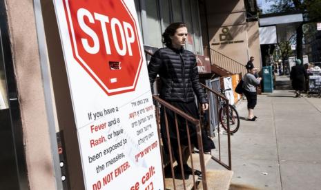  Warga berjalan melewati papan pengumuman peringatan tentang campak di luar klinik kesehatan  di kawasan Yahudi Ortodoks di lingkungan Williamsburg di Brooklyn, New York, AS, 25 April 2019. CDC kembali mengeluarkan peringatan sejak campak kembali merebak sejak Desember 2023 di AS.