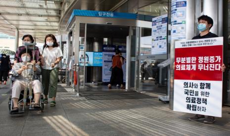 Seorang dokter yang melakukan unjuk rasa dokter (kanan) memegang poster saat melakukan protes terhadap kebijakan pemerintah, di depan Seoul National University Hospital di Seoul, Korea Selatan, 26 Agustus 2020. Dokter magang yang mengikuti mogok massal terkini terancam tindakan hukuman, seperti penangguhan lisensi medis.