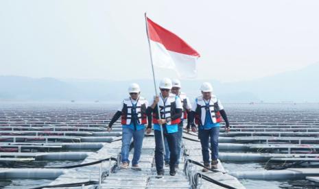 Direktur Utama PLN Darmawan Prasodjo (kedua dari kiri) berjalan di antara panel surya dengan menggenggam bendera merah putih saat meninjau (PLTS) terapung Cirata di Purwakarta, Jawa Barat 