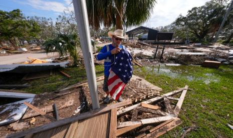 Warga mengibarkan bendera Amerika di atas reruntuhan balai kota, pasca Badai Helene, di Horseshoe Beach, Florida, Sabtu, 28 September 2024. 