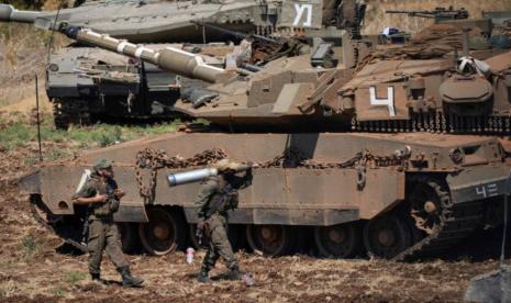 Seorang tentara Israel membawa peluru di samping tank di Israel utara pada Jumat, 27 September 2024.