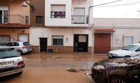 Seorang wanita melihat kondisi jalanan yang tertutup lumpur setelah hujan lebat yang menyebabkan banjir di La Alcudia, wilayah Valencia, Spanyol, Rabu (30/10/2024). 