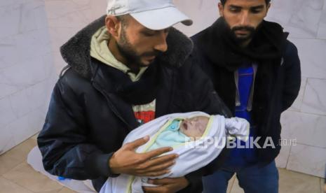 Mahmoud Al-Faseeh menggendong jenazah bayi perempuannya Sila (tiga pekan) yang syahid kedinginan, di Rumah Sakit Naser di Khan Younis Rabu 25 Desember 2024. 