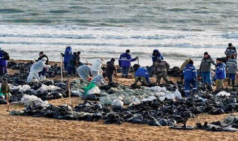 Relawan membantu membersihkan tumpahan minyak di area pantai yang tercemar akibat kecelakaan kapal tanker, di Rusia. 