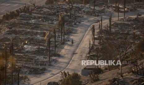 Seseorang berjalan melalui lingkungan yang hancur akibat kebakaran di bagian Pacific Palisades di Los Angeles, Jumat, 10 Januari 2025. 