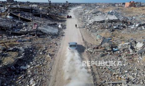 Sebuah mobil di jalan saat warga Palestina berjalan melewati kehancuran akibat serangan udara dan darat Israel di Rafah, menyusul perjanjian gencatan senjata, Ahad 19 Januari 2025.