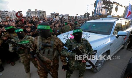 Pejuang Hamas mengawal kendaraan Palang Merah untuk mengumpulkan sandera Israel yang dibebaskan di Kota Gaza Ahad , 19 Januari 2025.