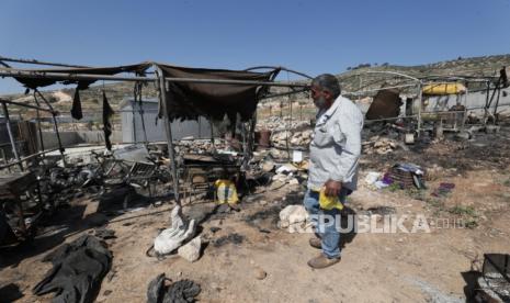 Seorang pria Palestina memeriksa bangunan yang terbakar pemukim Israela di desa Al-Mughayyir, Tepi Barat, dekat Ramallah (ilustrasi)