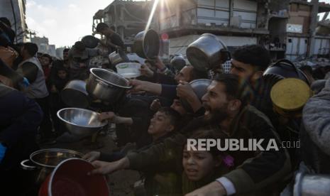 Anak-anak pengungsi Palestina antri untuk menerima porsi makanan dari dapur amal sebelum berbuka puasa, di Beit Lahia, Jalur Gaza utara, 10 Maret 2025.