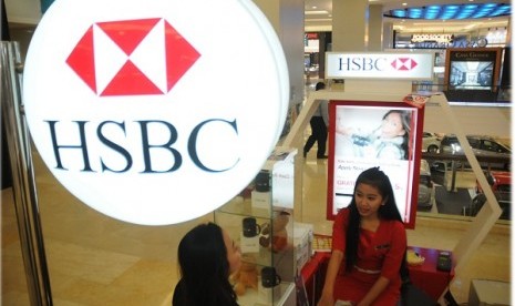 A bank teller of HSBC deals with a customer in a service counter. (illustration)