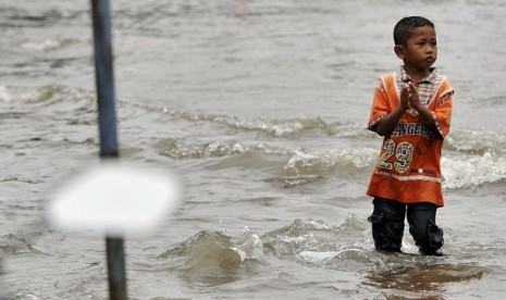 A boy walks in an inundated street. (illustration)