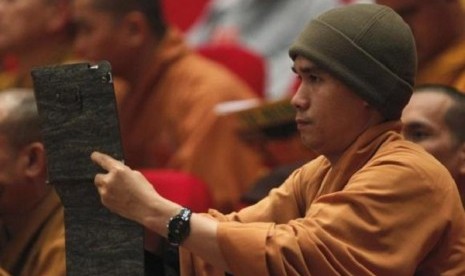 A Buddhist monk films, with an iPad, the closing ceremony of the seventh congress of Vietnam's Buddhist Sangha Association in Hanoi November 24, 2012.