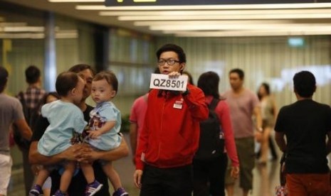 A Changi Airport staff holds up a sign to direct possible next-of-kins of passengers of AirAsia flight QZ 8501 from Indonesian city of 