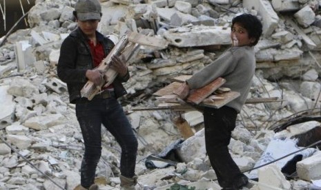 A child blows a bubble gum while collecting firewood amid damage and debris after what activists said was an air strike by forces loyal to Syria's President Bashar al-Assad in the Al-Maysar neighbourhood of Aleppo February 23, 2014.